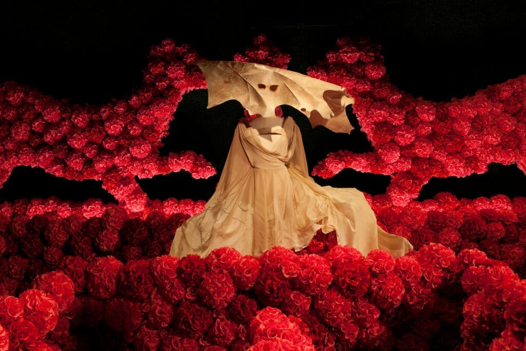a dress with a mask on it surrounded by red roses