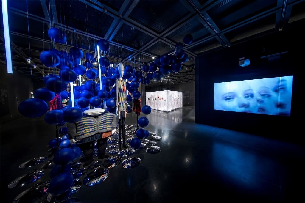 a room with blue balloons and a large screen